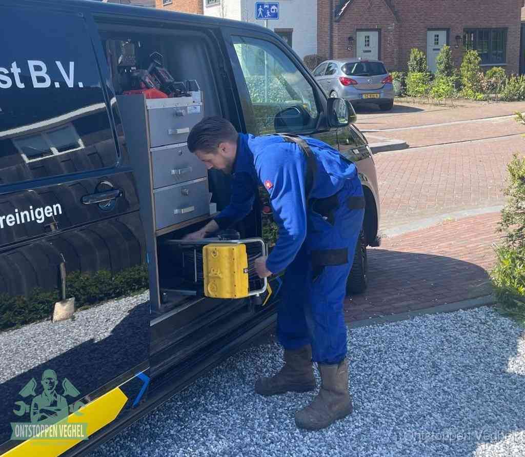 Een monteur pakt buiten op de oprit gereedschap uit de bedrijfsbus, het moment om een professional in te schakelen voor een verstopte afvoer in Veghel