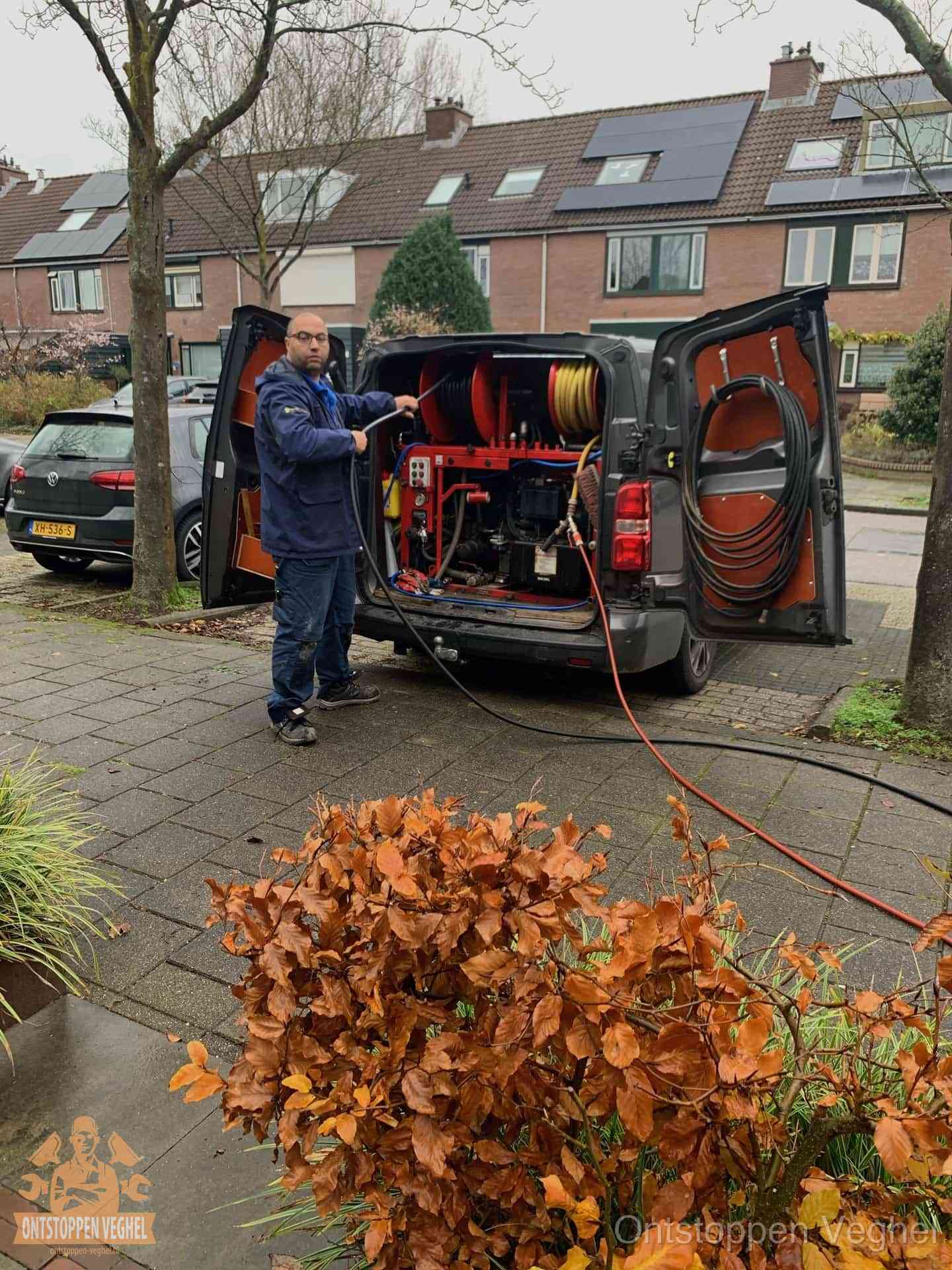 Monteur met rioolreinigingsbus levert rioolservice in de wijk in Veghel