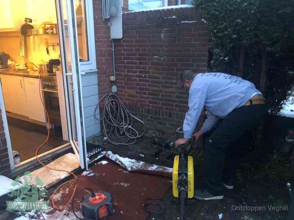 Een monteur werkt buiten bij een open riool-/grondput met een elektrische ontstoppingsmachine om een verborgen afvoerprobleem op te sporen in Veghel