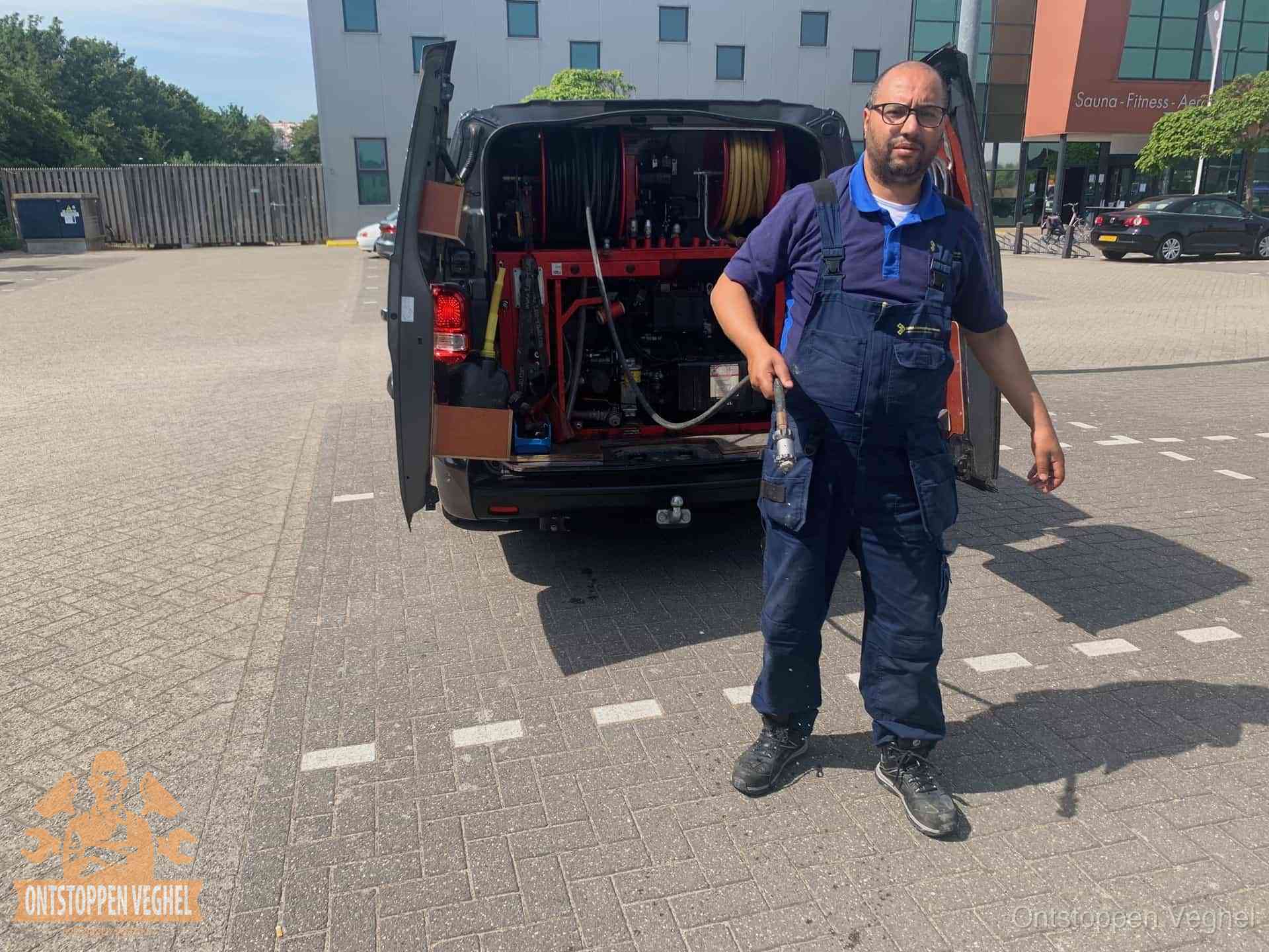 Terugkerende wc-verstoppingen aanpakken in Veghel Een monteur bij zijn bestelbus met een hogedruk- en rioolreinigingsunit, klaar om de oorzaak van terugkerende wc-verstoppingen aan te pakken in Veghel
